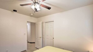 A bedroom with a bed, a ceiling fan, and a door. - Inviting Bakersfield Home w/ Spacious Yard! (Bakersfield)