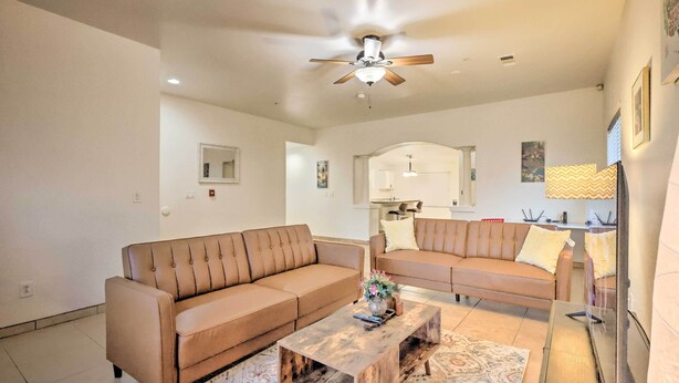 A spacious living room with two beige sofas, a wooden coffee table, and a ceiling fan. - Inviting Bakersfield Home w/ Spacious Yard! (Bakersfield)