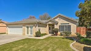 A single-story house with a garage, a front yard with a lawn, and a wooden fence. - Inviting Bakersfield Home w/ Spacious Yard! (Bakersfield)