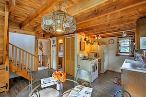 Un intérieur en bois avec une table en verre, un vase de fleurs, un coin cuisine et un escalier.