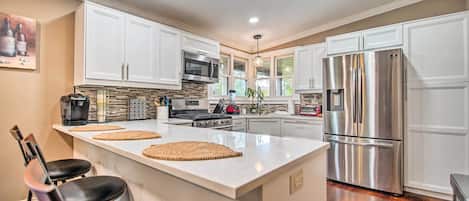 A modern kitchen with white cabinets, stainless steel appliances, and a central island with stools.