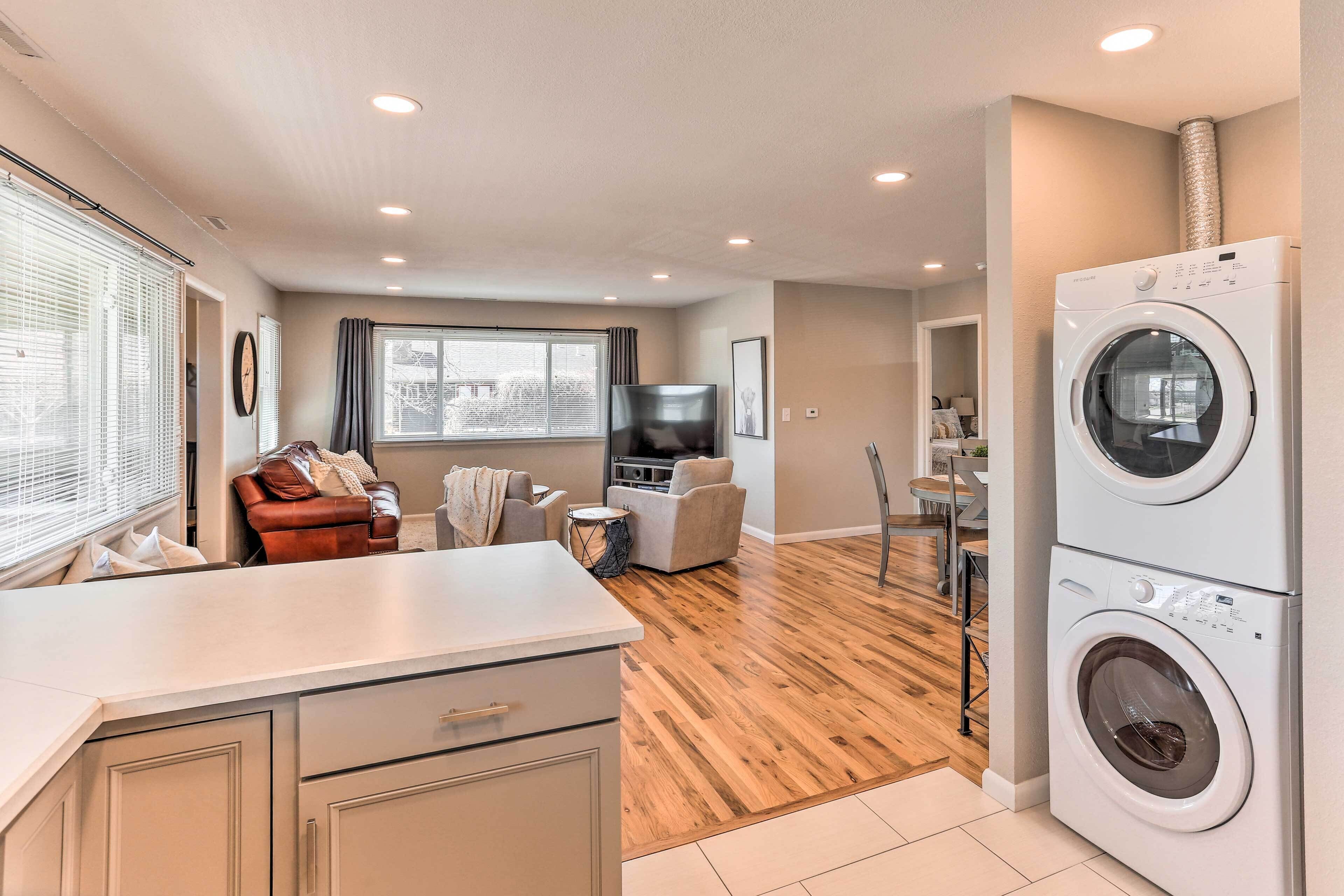 Un espacio habitable compacto con kitchenette, un sofá, una zona de comedor y una lavadora.