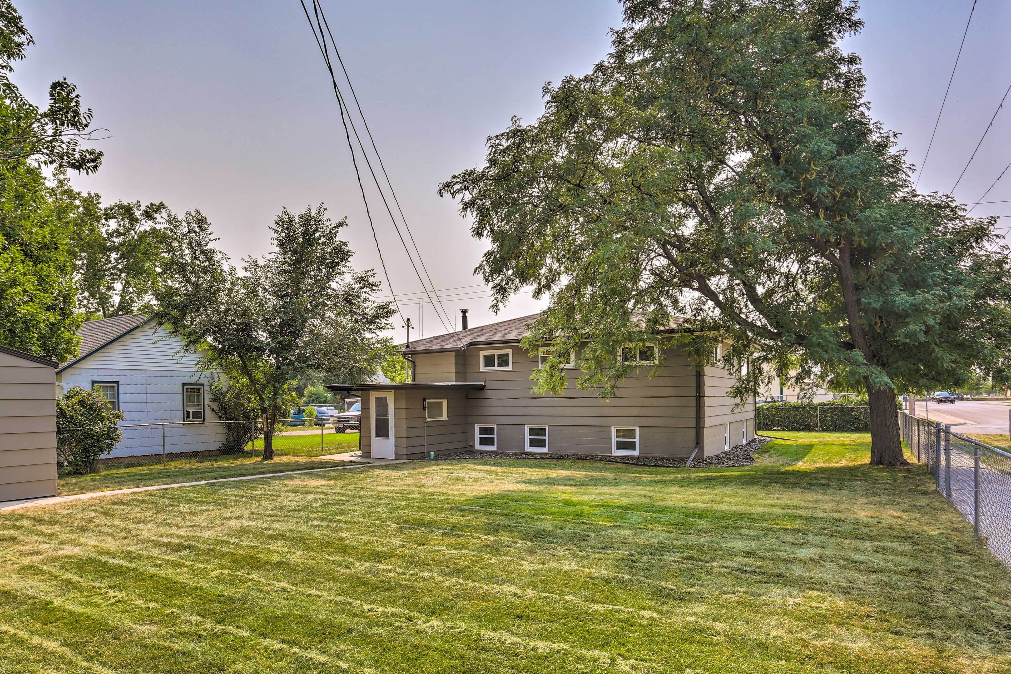 A residential property with a well-maintained lawn, a detached garage, and a large tree providing shade.