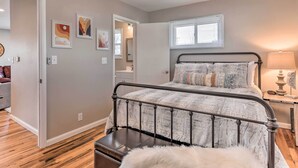 A bedroom with a bed, a bench, a nightstand, and a window.