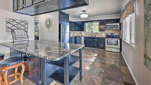 A modern kitchen with dark cabinetry, a granite countertop, and stainless steel appliances.