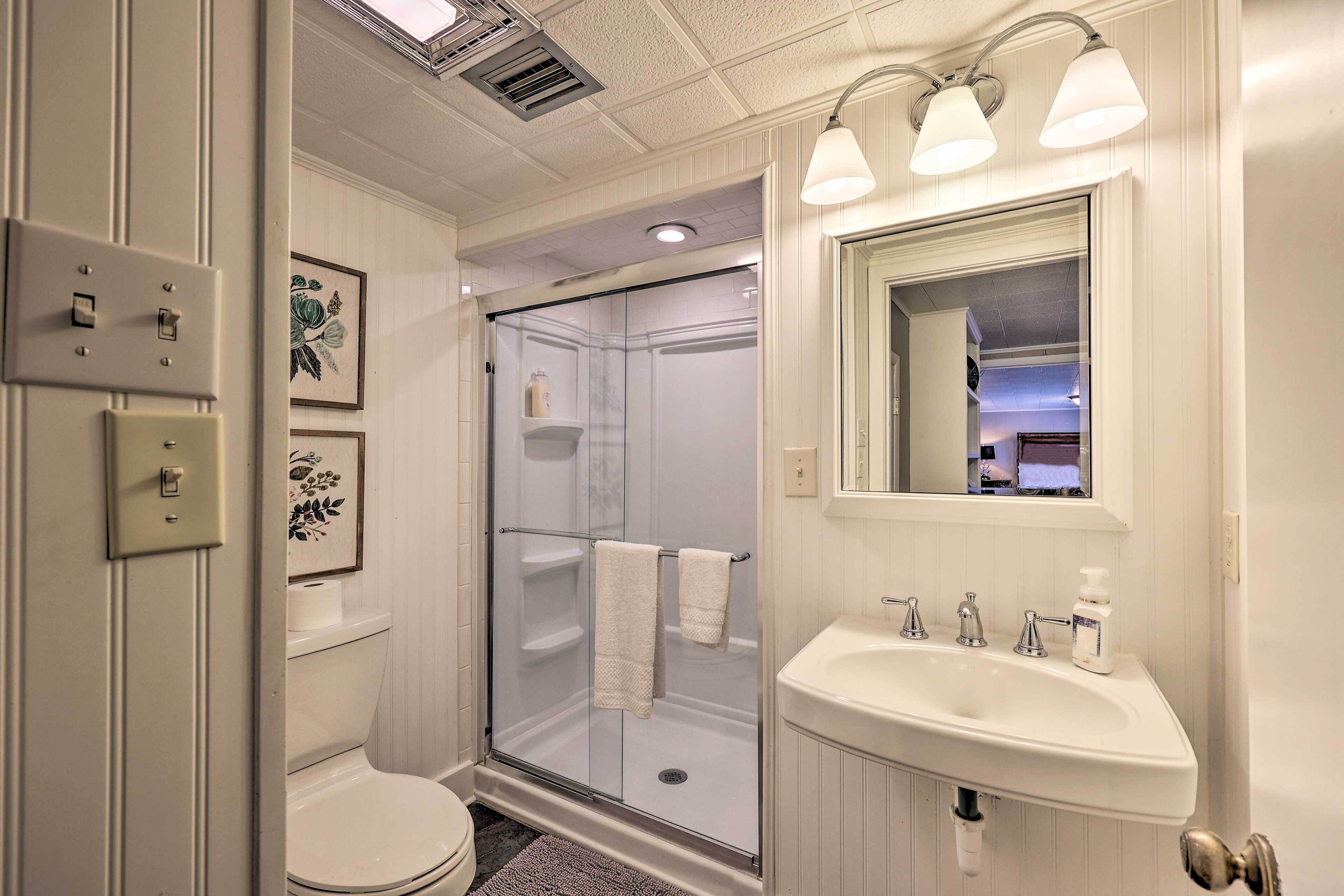 A bathroom with a glass-enclosed shower, a white sink, and a mirror above it.