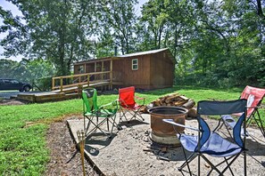 Een rustieke blokhut met een houten terras, omringd door weelderig groen.