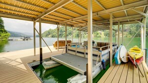 A covered boat dock with a wooden deck, a small boat, and kayaks. - Lakefront Butler Retreat w/ Hot Tub & Dock! (Butler)