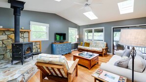 A cozy living room with a stone fireplace, wooden furniture, and large windows. - Lakefront Butler Retreat w/ Hot Tub & Dock! (Butler)