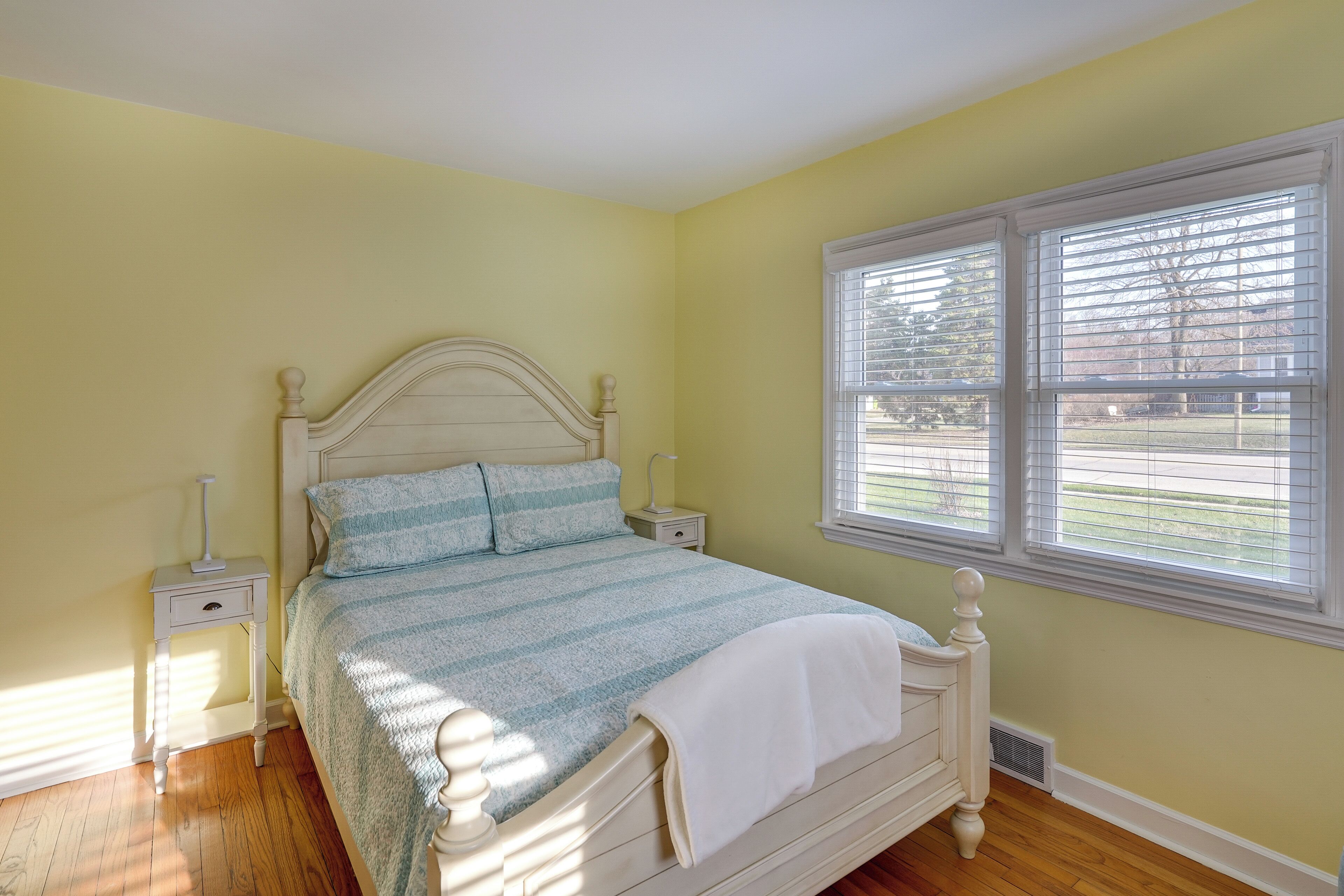 Une chambre à coucher avec un lit, des tables de chevet et une fenêtre avec des stores.