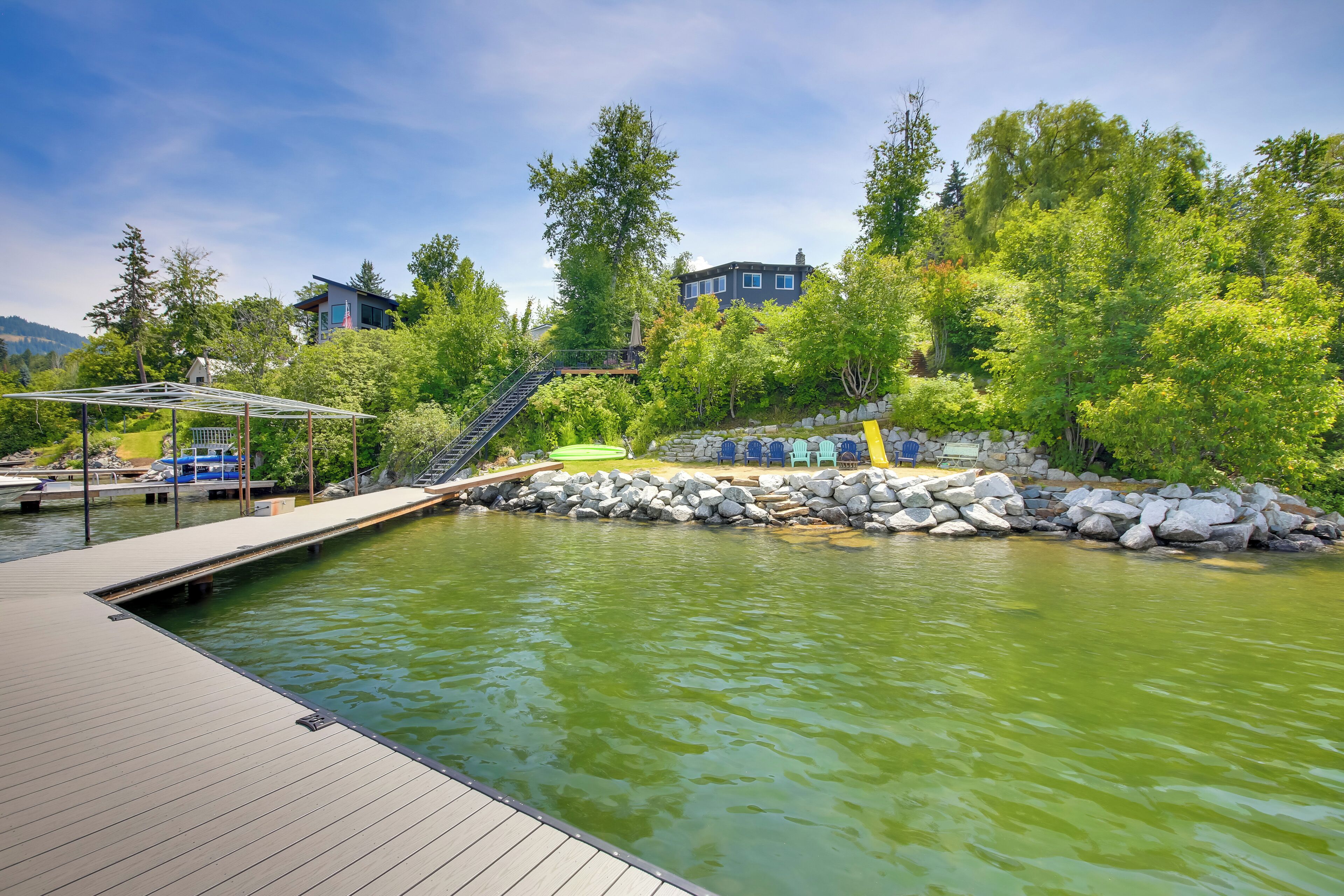 A wooden deck with a pool, surrounded by rocks and trees.