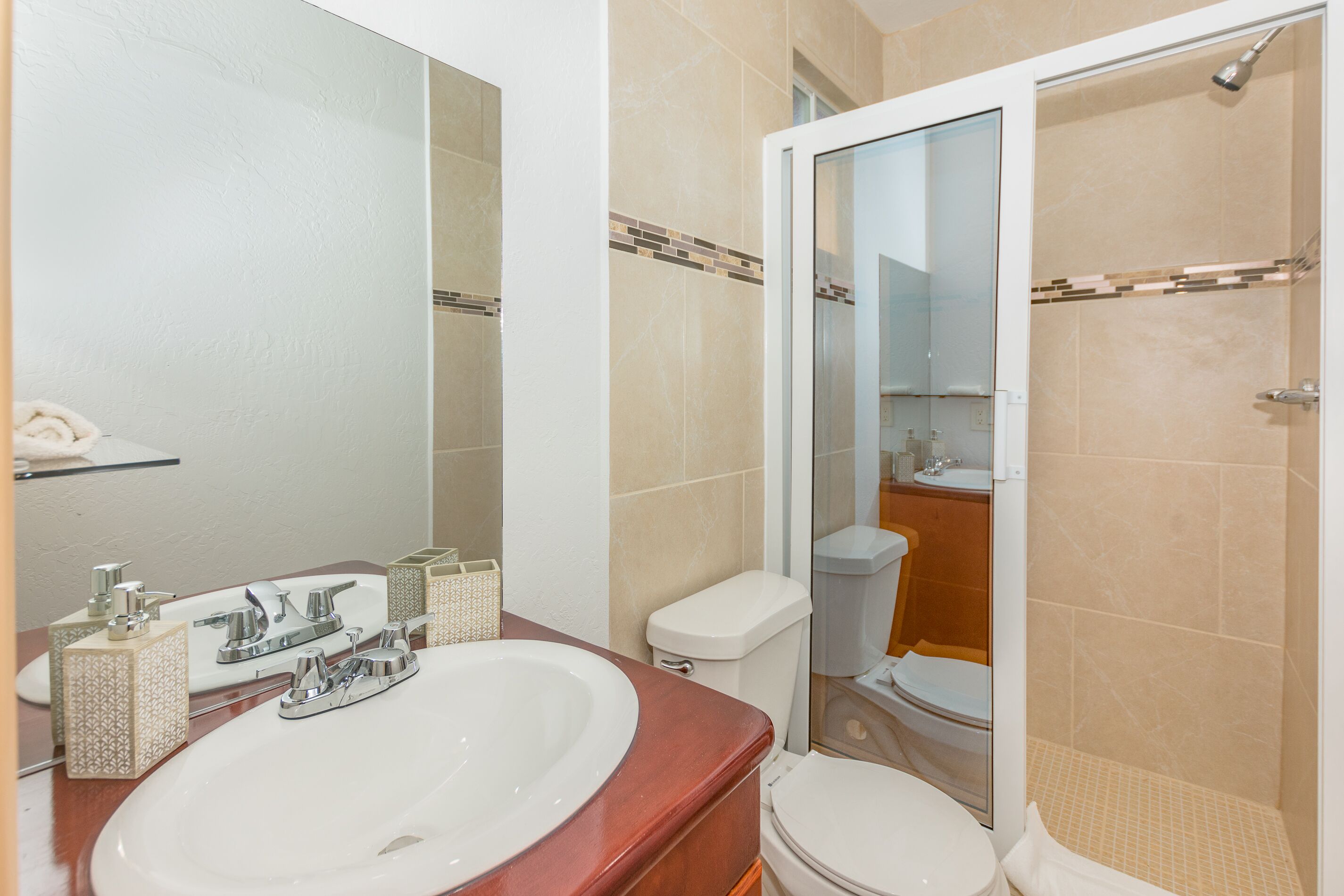 Un baño con lavamanos, espejo, inodoro y ducha.