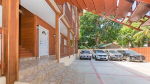 Ein Gebäude mit Holzfassade, Treppe zum Eingang und ein Parkplatz mit mehreren Autos.