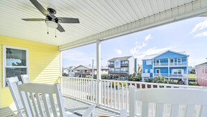 A covered porch with white railings, a ceiling fan, and wicker chairs. - Freshly Remodeled Beach House, Steps to Shore (Sunset Beach)