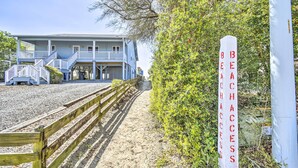A beachfront property with a wooden staircase leading to a building with a balcony. A sign indicates beach access. - Freshly Remodeled Beach House, Steps to Shore (Sunset Beach)