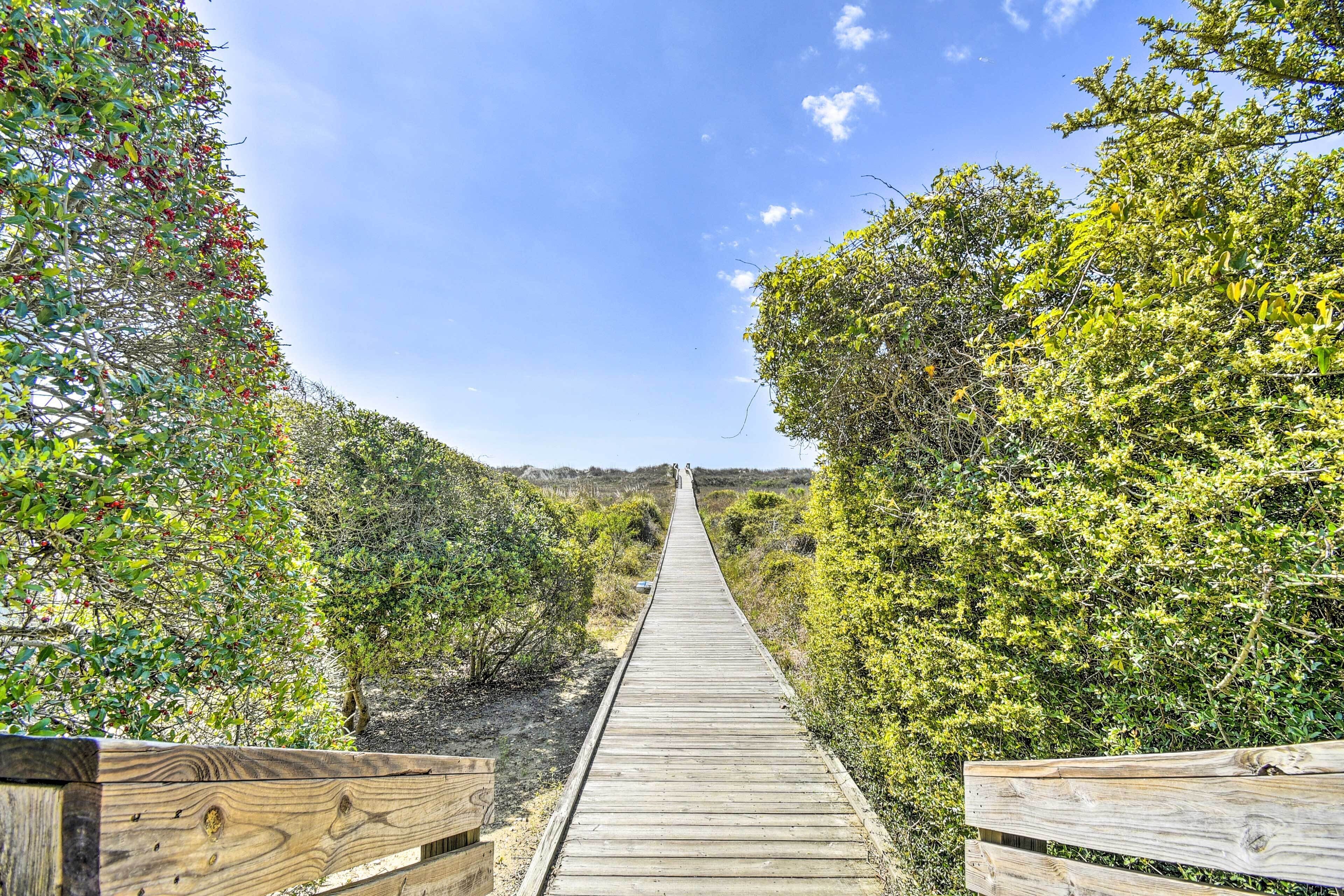 A wooden boardwalk leading through a natural landscape with dense vegetation on both sides.