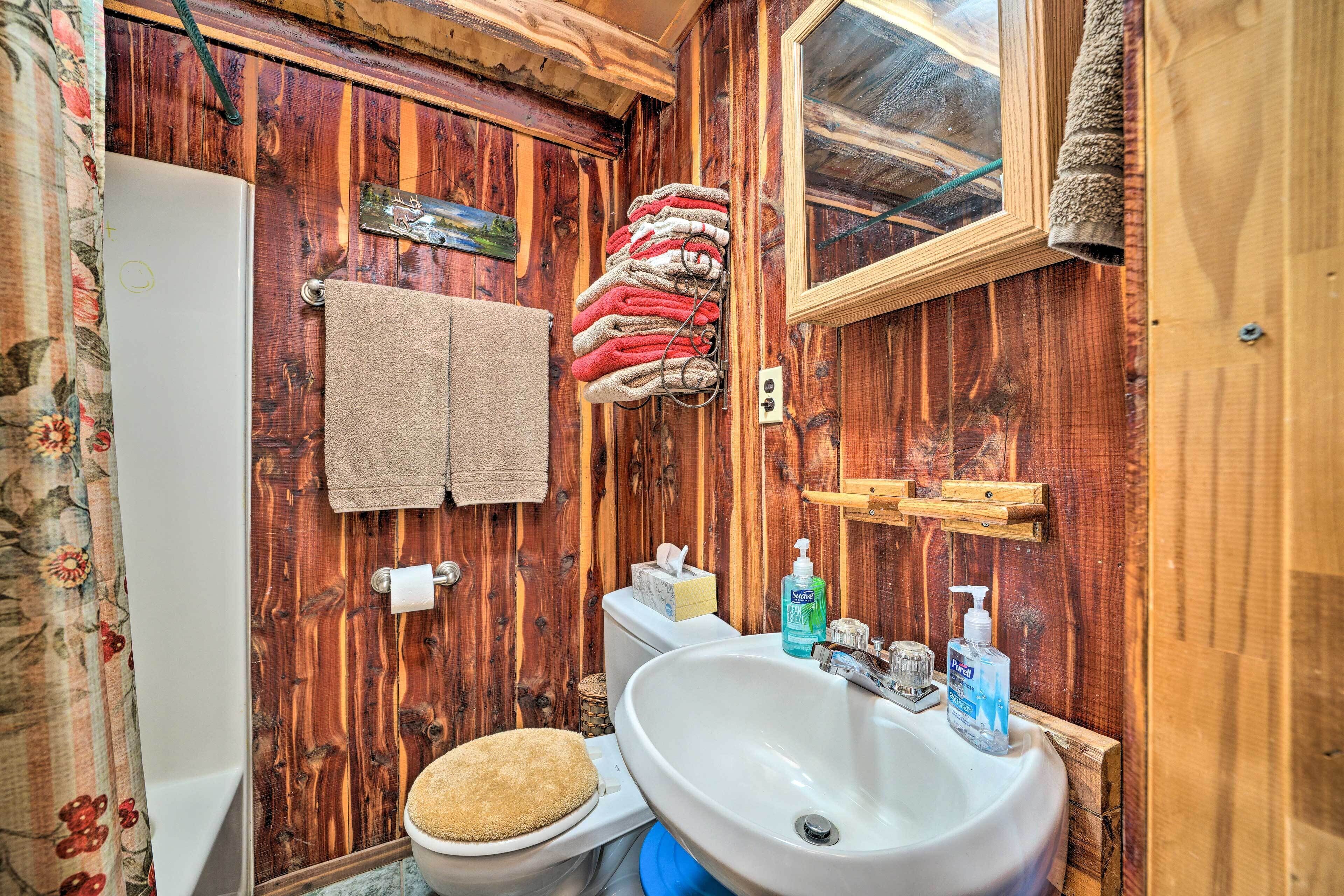 Een houten badkamer met toilet, wastafel en spiegel.