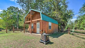 A rustic cabin with a green roof, a porch, and a small outdoor seating area. - Hand-built 'black Fork Cabin 2' w/ Fire Pit! (Nashoba)