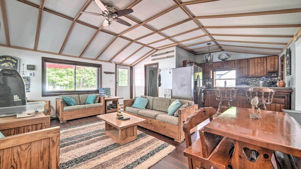 A spacious living area with wooden furniture, a large dining table, and a kitchen in the background. - Jamestown Retreat w/ Hot Tub - Walk to Lake! (Westford)