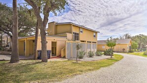 A two-story yellow building with a covered patio and a gravel driveway.