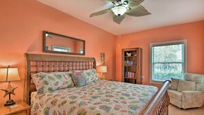A bedroom with a bed, a chair, a bookshelf, a starfish lamp, and a ceiling fan.