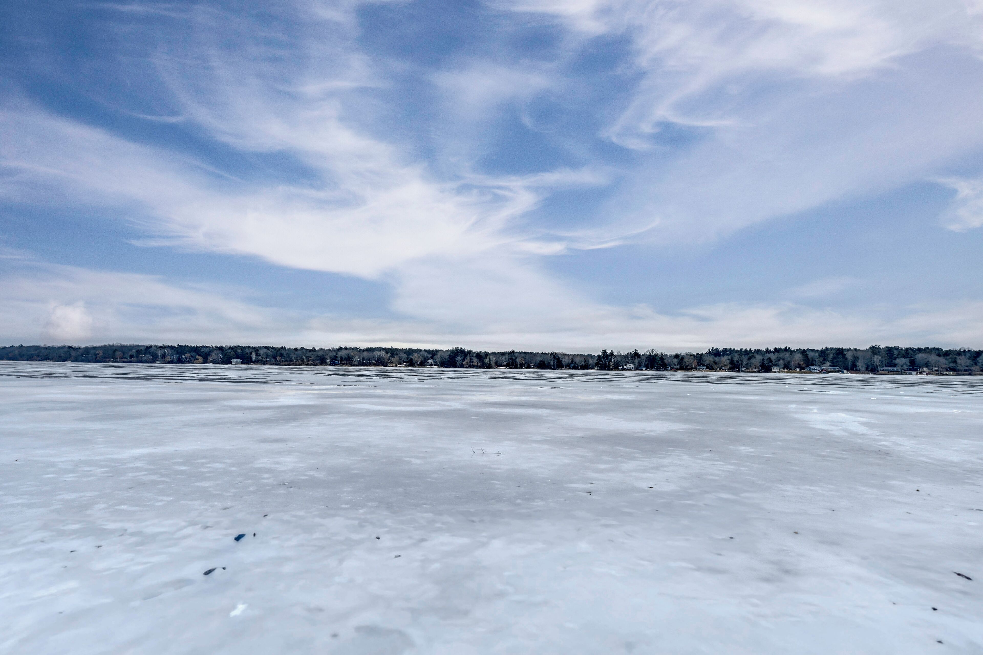 A frozen landscape with a clear sky and distant trees.
