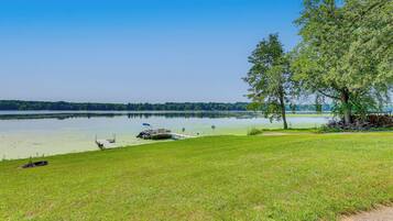A lakeside view with a grassy area, dock, and boats.