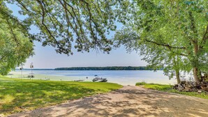 Un chemin pavé mène à une zone au bord du lac, où se trouvent des bateaux et un quai.