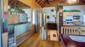 A spacious kitchen with wooden cabinets, a dining area with a wooden table, and a staircase leading to an upper level. - 'ledge Lodge' Burkesville Getaway: Pool & Views! (Burkesville)