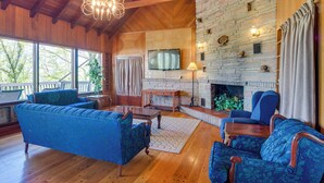 A spacious living room with a stone fireplace, wooden ceiling beams, and large windows. - 'ledge Lodge' Burkesville Getaway: Pool & Views! (Burkesville)