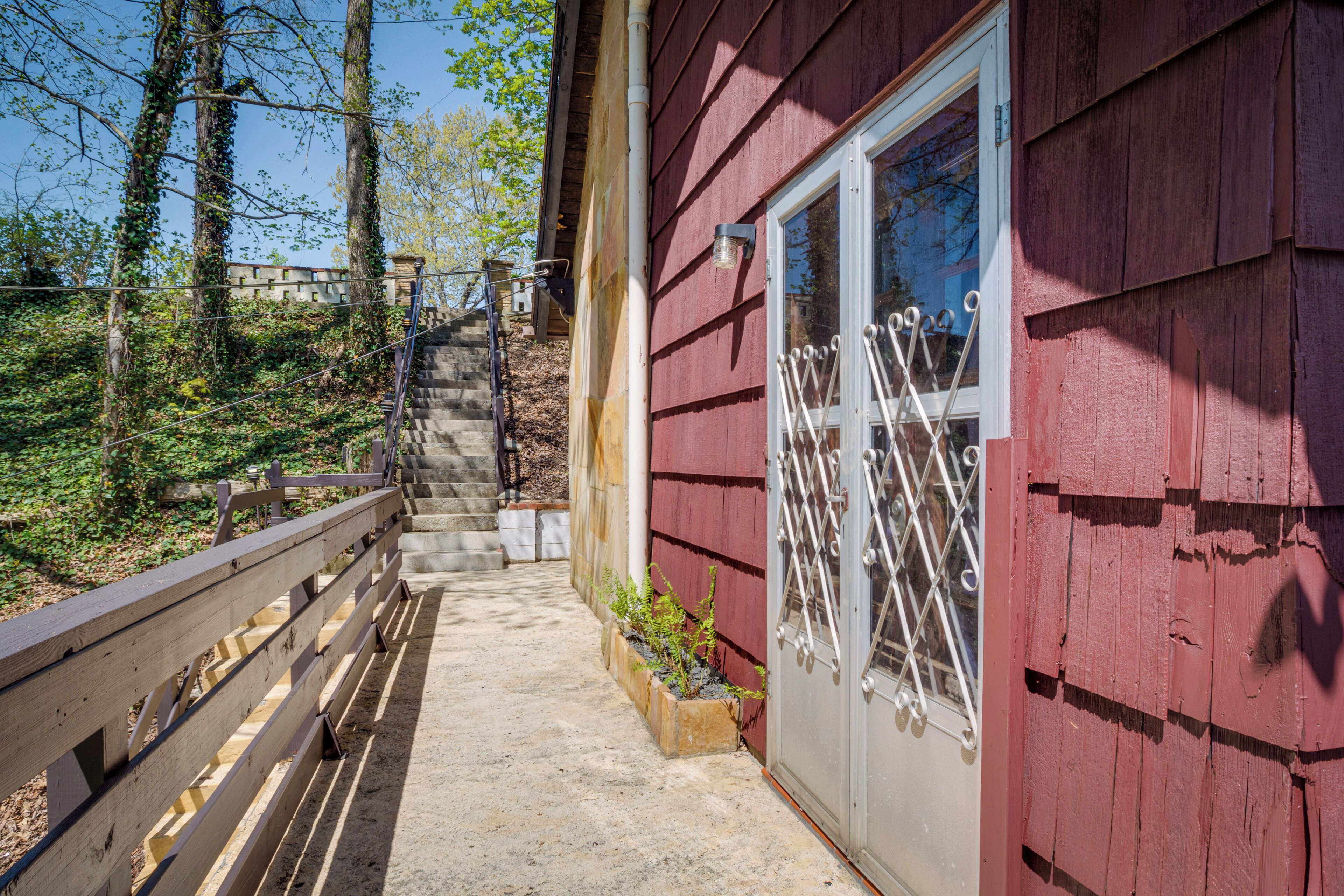 A wooden staircase leading to a red building with a metal gate and a window.