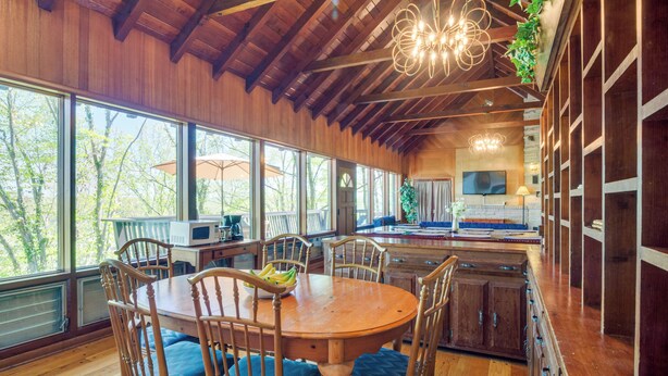 A spacious kitchen with wooden cabinets, a dining table with chairs, and large windows offering a view of trees. - 'ledge Lodge' Burkesville Getaway: Pool & Views! (Burkesville)