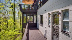 A wooden deck with a glass balustrade, a balcony with an umbrella, and a white building with multiple windows. - 'ledge Lodge' Burkesville Getaway: Pool & Views! (Burkesville)