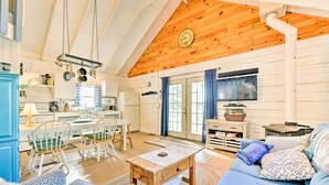 A cozy living room with a wooden ceiling, a blue sofa, patterned cushions, a wooden coffee table, and a television.