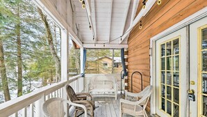 A wooden porch with wicker rocking chairs and a white railing.