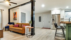 Un salon moderne avec un canapé, une table basse et un coin bar équipé de tabourets.