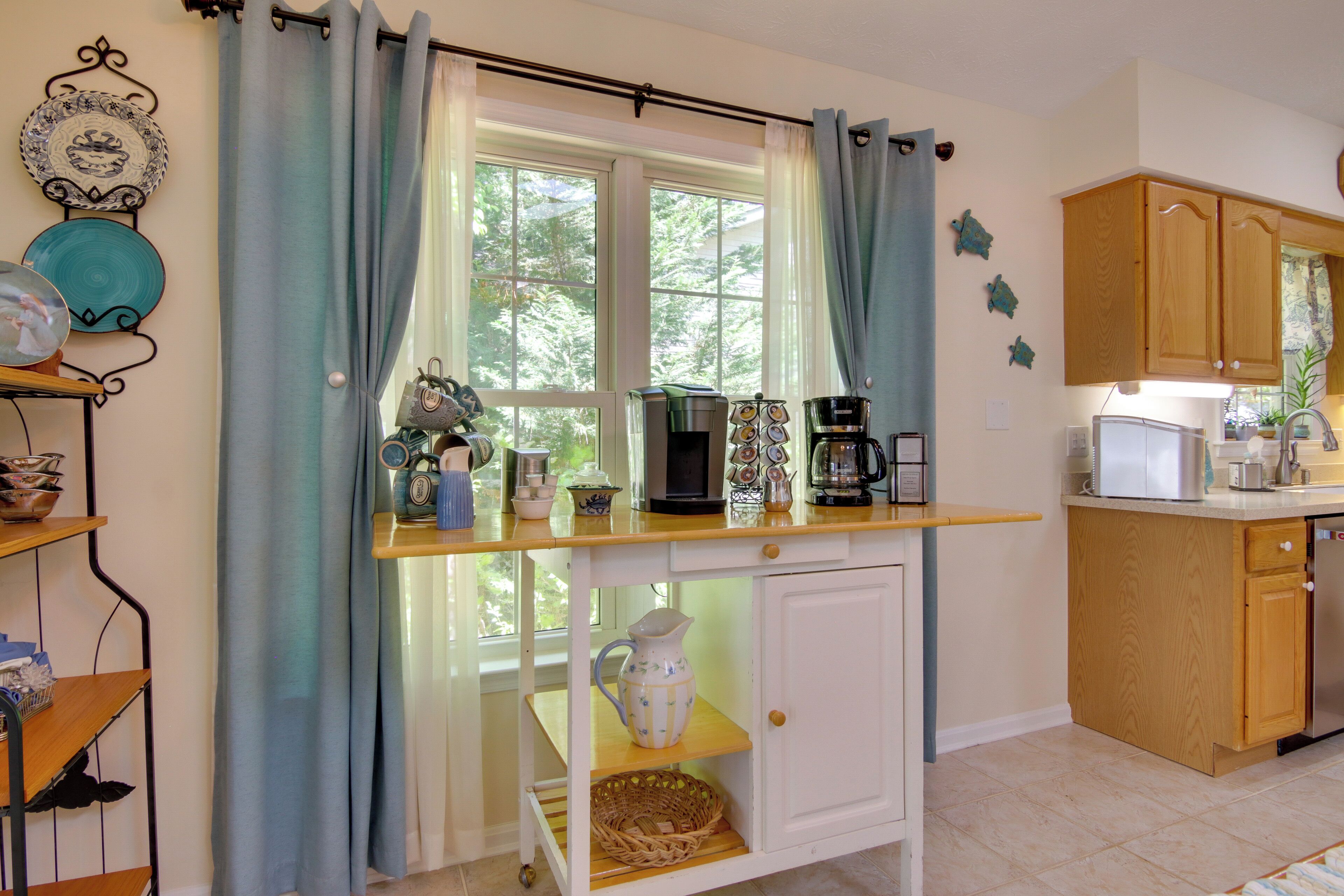 A kitchen with a window, a countertop with various appliances, and wooden cabinets.