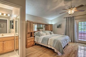 A bedroom with a bed, wooden cabinets, a vanity with a mirror, and a ceiling fan. - 2 Mi to Golf: Hot Tub Hideaway in Ocean Pines (Berlin)