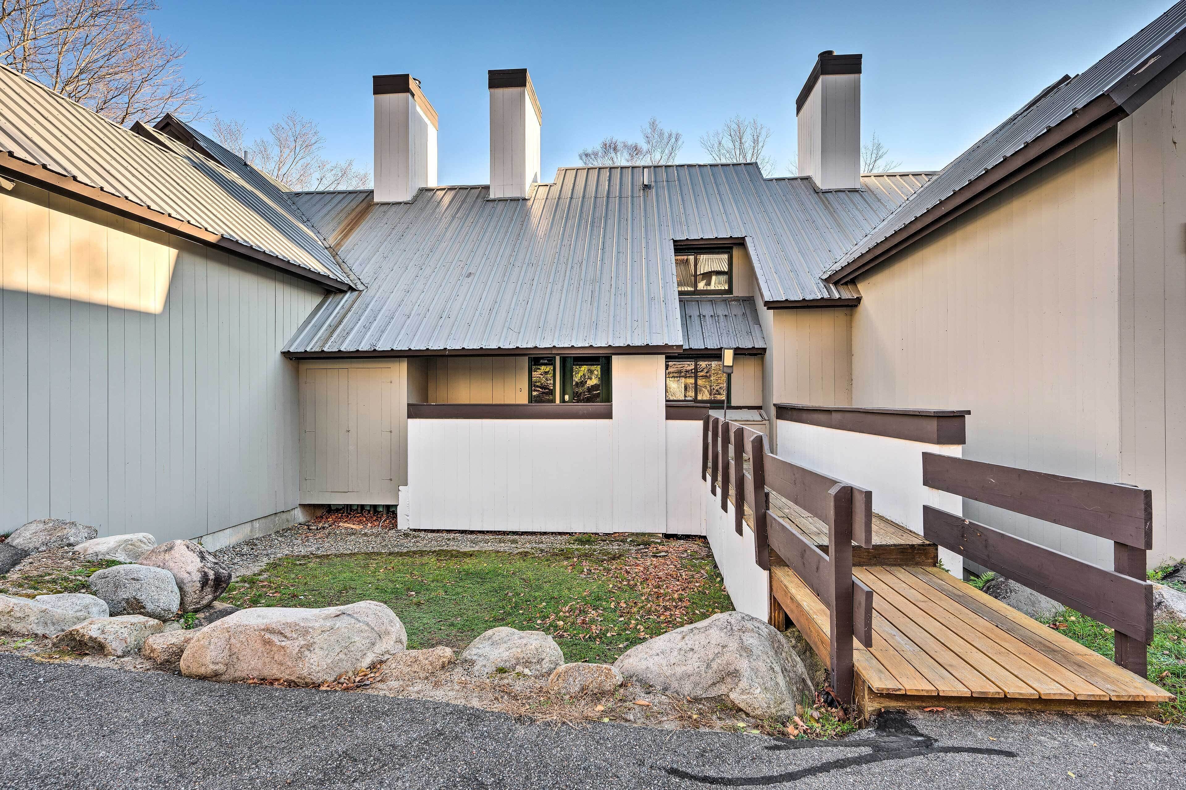 A building with a metal roof, a wooden deck, and a gravel area with rocks.