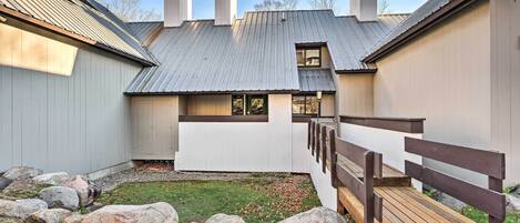 A building with a metal roof, a wooden deck, and a gravel area with rocks.