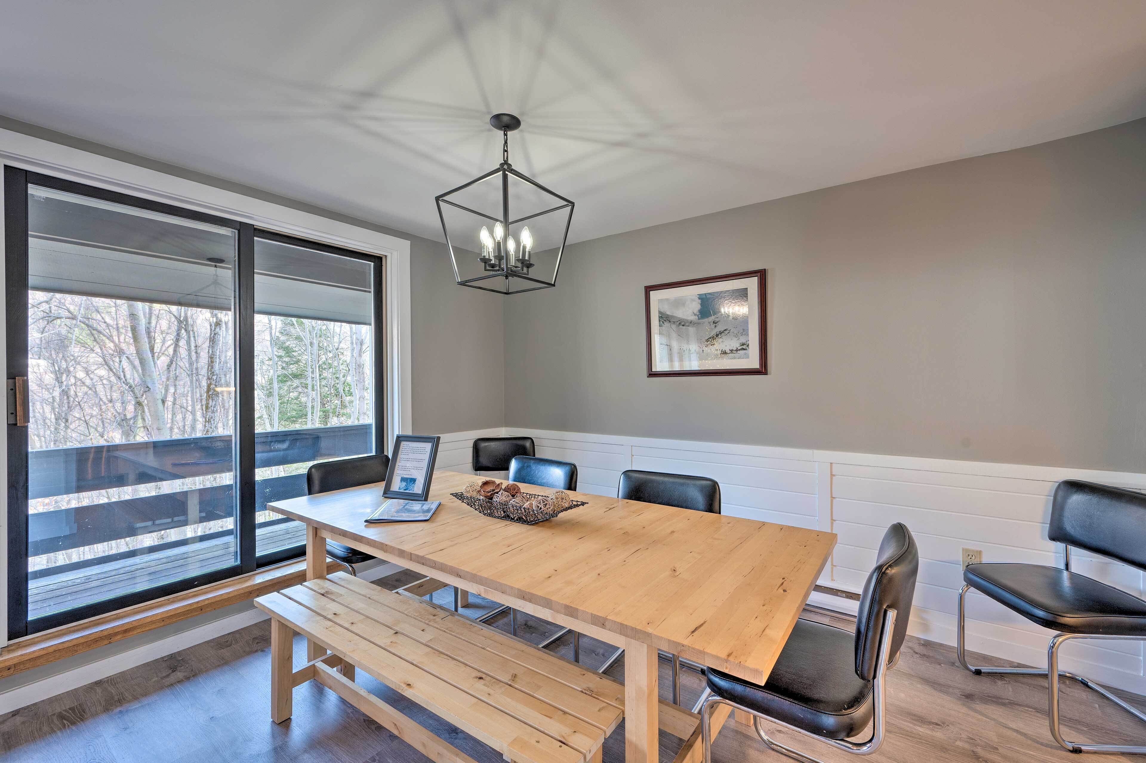 A dining area with a wooden table, black chairs, and a chandelier.