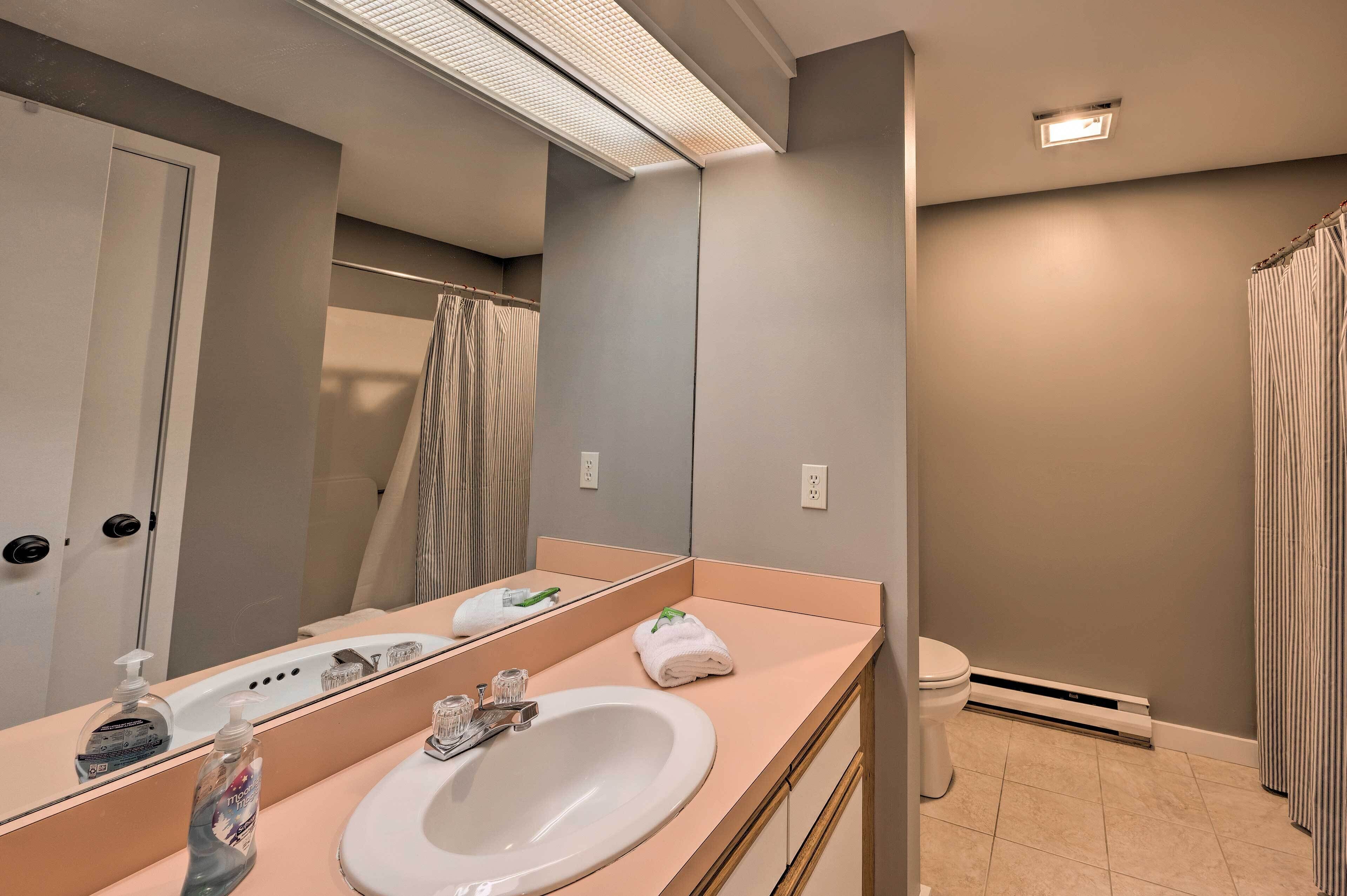 A bathroom with a large mirror, a sink, a toilet, and a shower curtain.