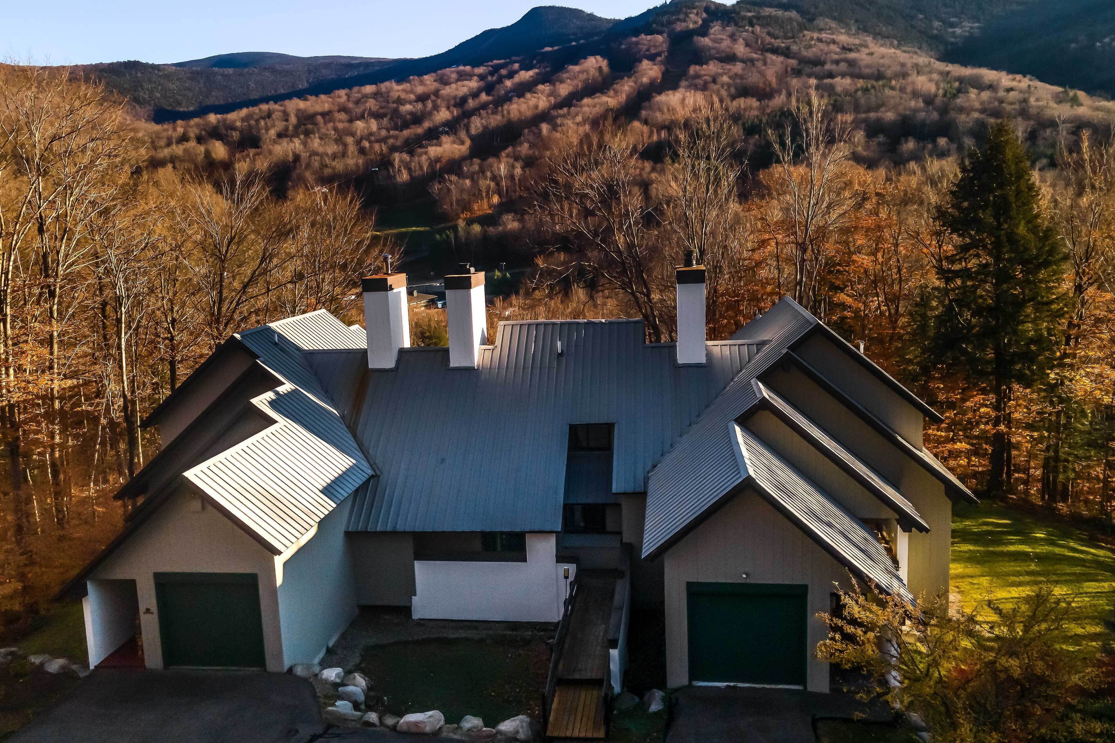 A modern two-story house with a central chimney, two garages, and a small deck.