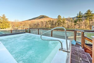 Un jacuzzi con cubierta de madera y baranda de metal, con vistas a un paisaje montañoso.