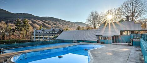 A swimming pool with a view of mountains and a building in the background.