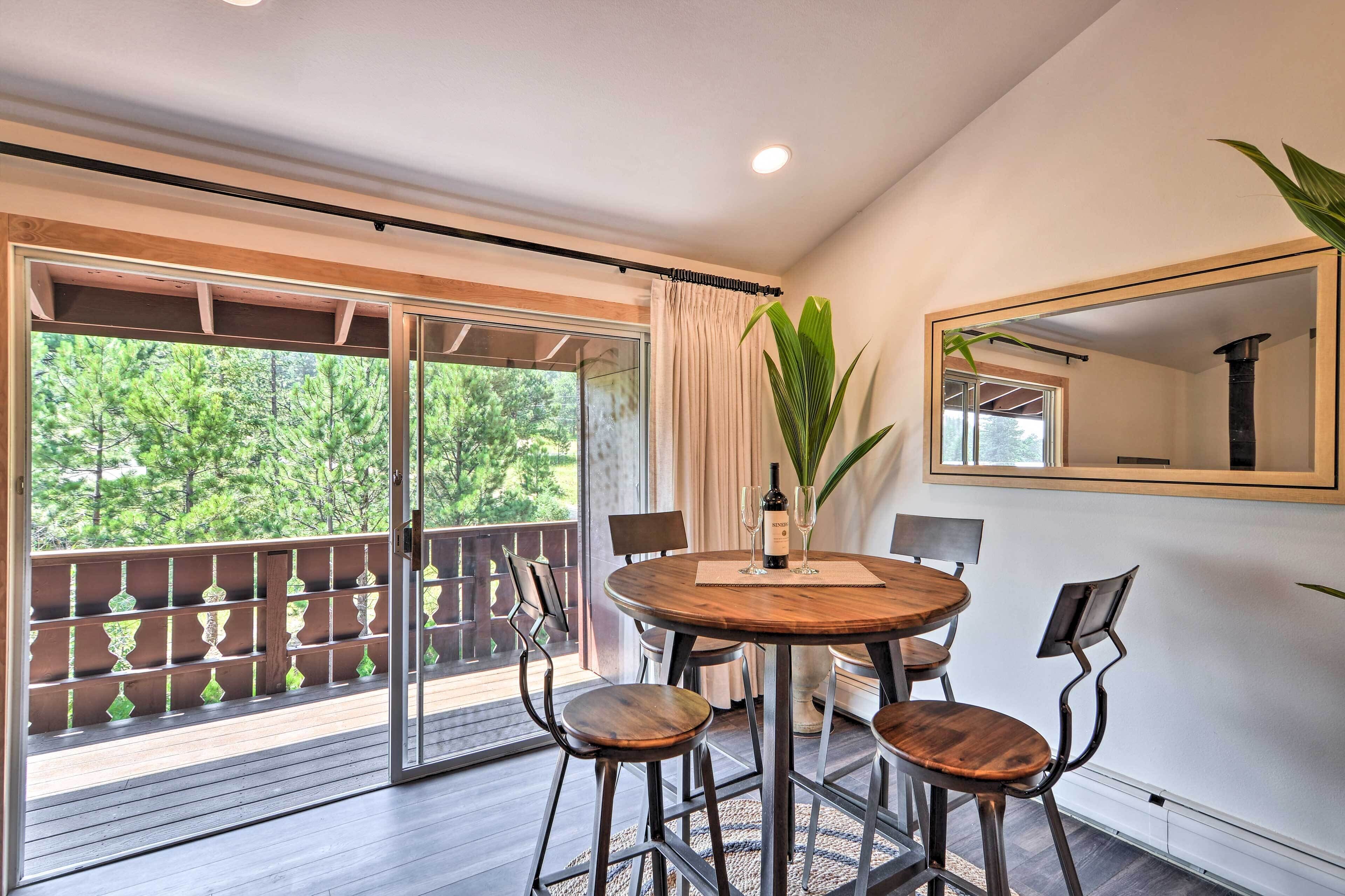 A dining area with a round wooden table, four chairs, and a large potted plant.