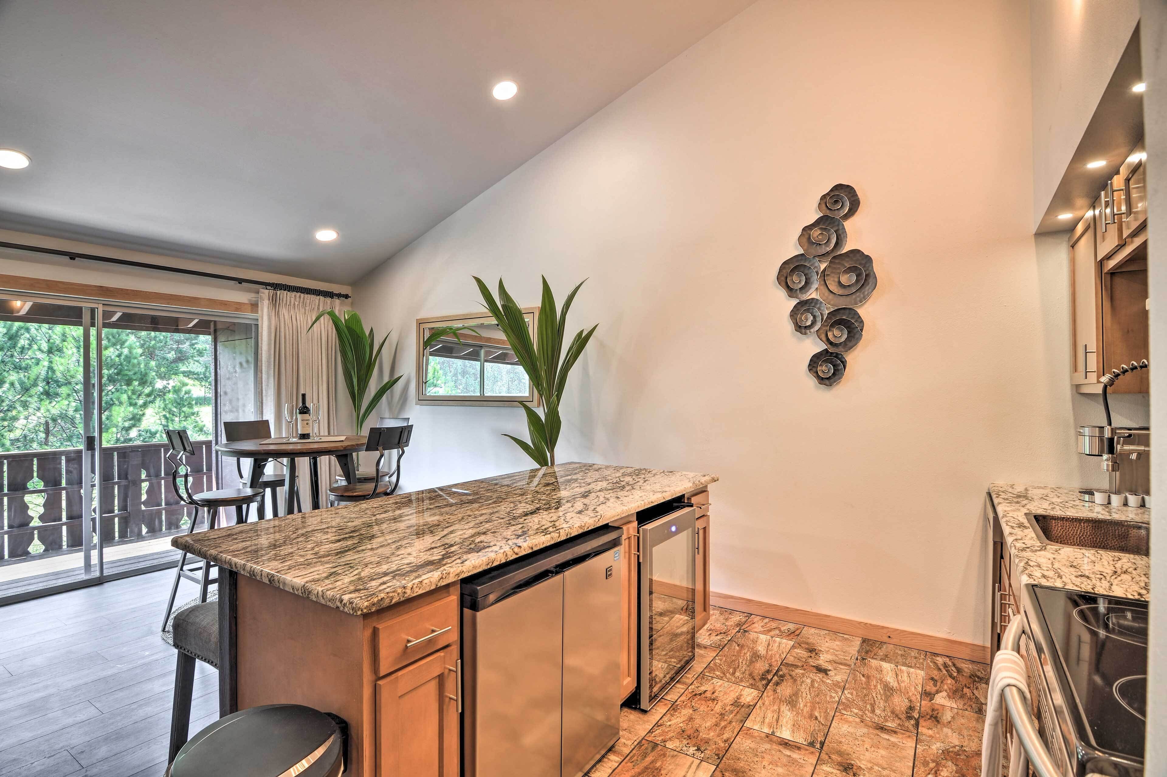 A modern kitchen with a granite countertop, stainless steel appliances, and a dining area with a table and chairs.