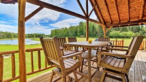 Eine Holzterrasse mit Gartenmöbeln mit Blick auf einen See und einen Wald.