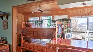 A cozy cabin room with a bunk bed, a wooden table, and a ceiling fan. - 'paradise Cove' Cabin w/ Boathouse & Dock (Guntersville)