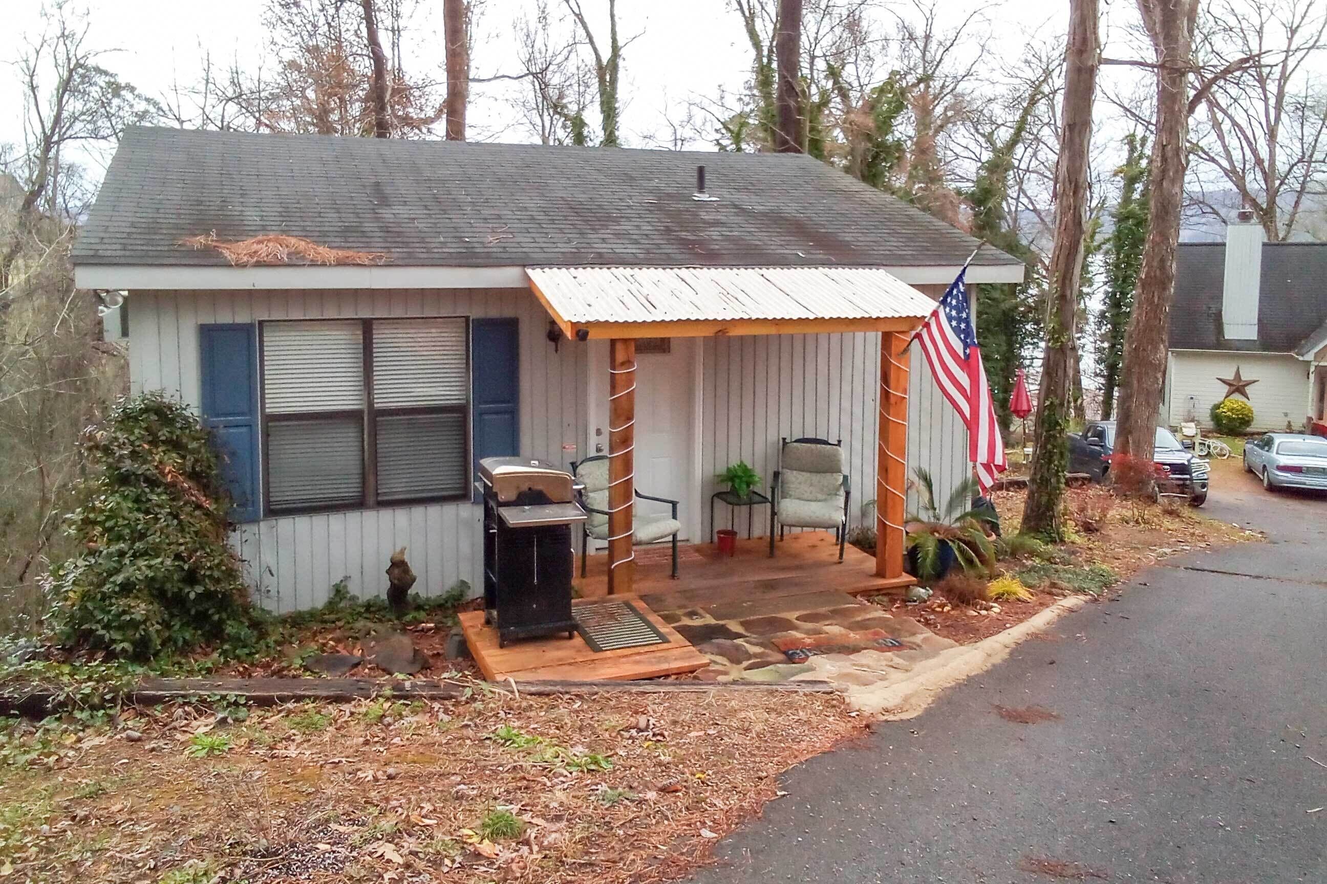 A small, single-story house with a porch, an American flag, and a small garden area.
